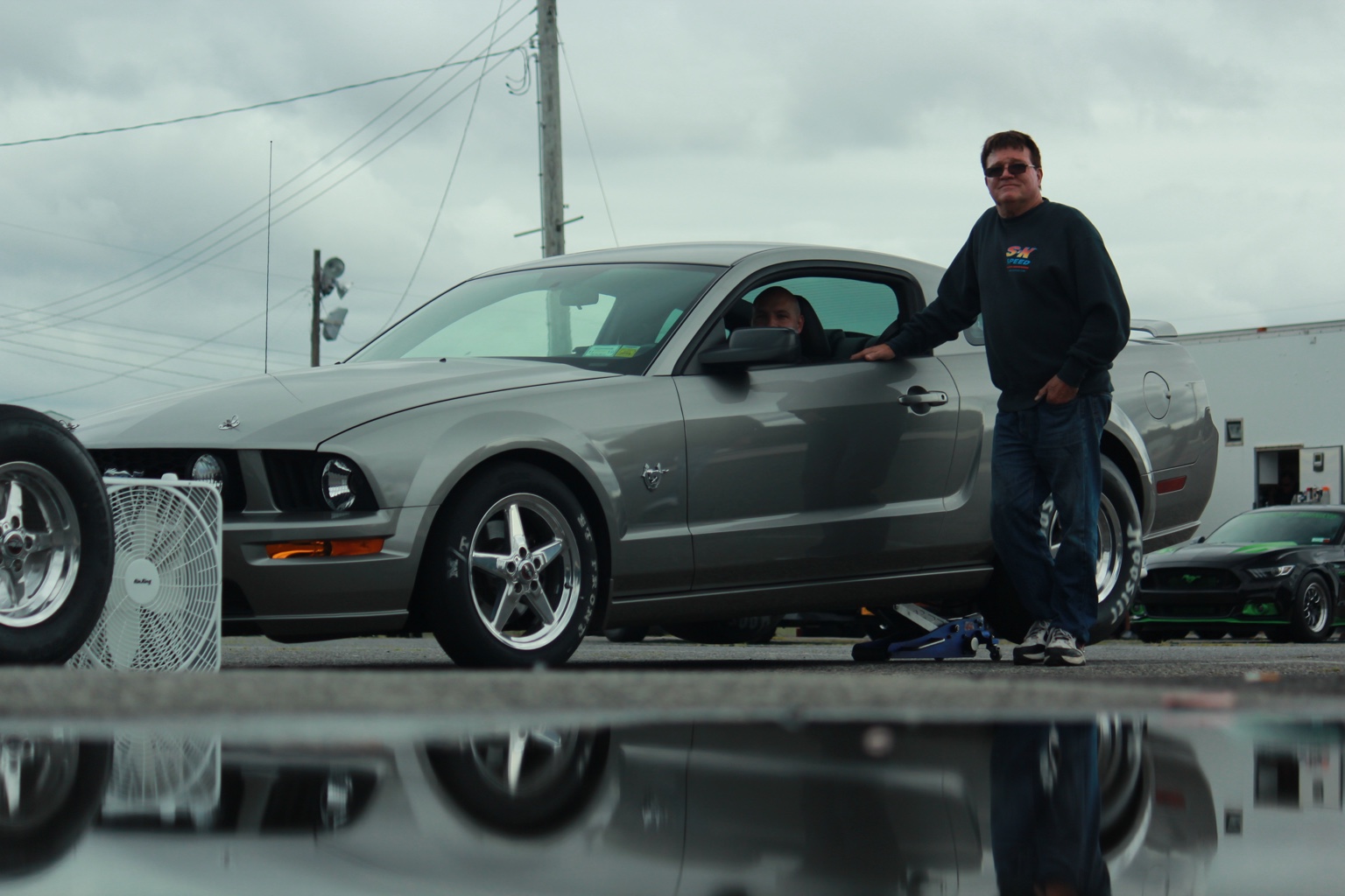Glenn's father standing beside the family's silver Mustang GT